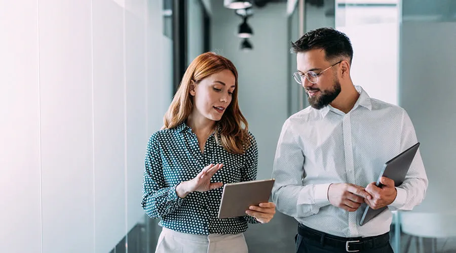 Dos personas en el pasillo de la oficina revisando una tablet