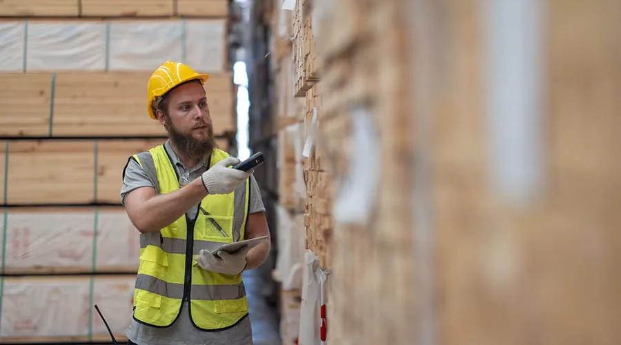 Trabajador verifica los artículos de paletas de madera utilizando un dispositivo portátil Trabajador verifica los artículos de paletas de madera utilizando un dispositivo portátil