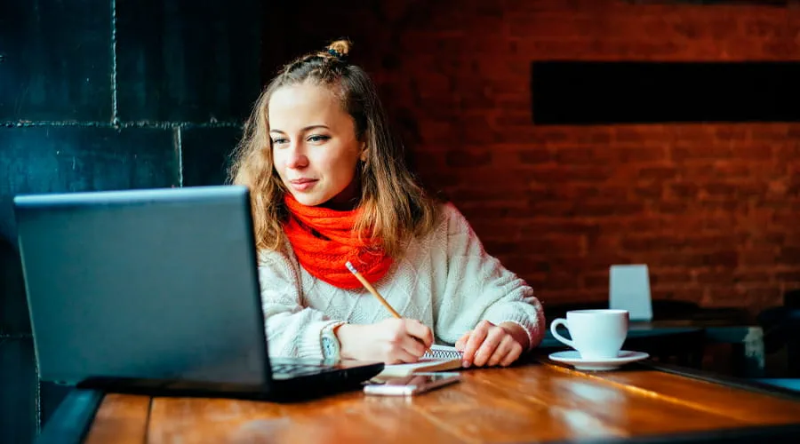 Mujer trabajando desde casa con una computadora y un café en la mesa