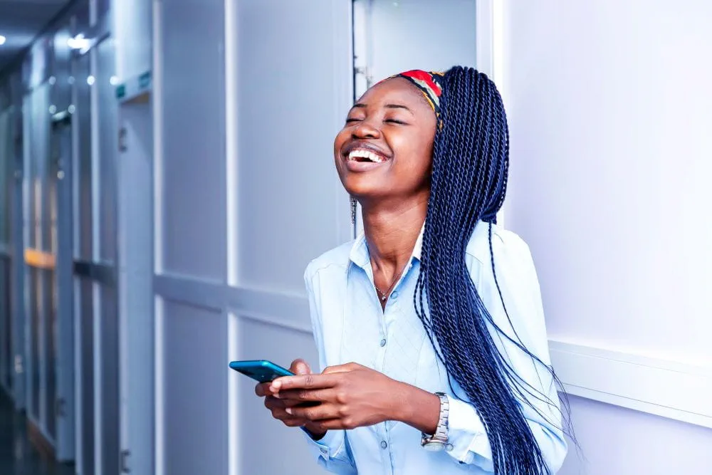 Une candidate heureuse consultant un SMS de l’assistant IA Adecco Une candidate heureuse consultant un SMS de l’assistant IA Adecco