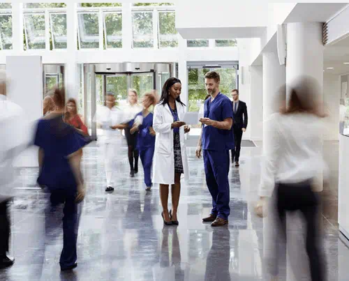 Un hall d'hôpital moderne et animé avec au centre une femme et un homme en blouse discutant et des personnes se déplacent autour Un hall d'hôpital moderne et animé avec au centre une femme et un homme en blouse discutant et des personnes se déplacent autour