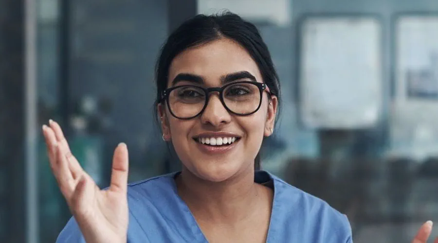 Une professionnelle de la santé souriante et portant des lunettes, parle avec deux collègues Une professionnelle de la santé souriante et portant des lunettes, parle avec deux collègues