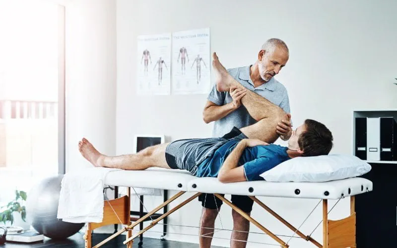 Un kinésithérapeute manipule la jambe d’un patient Un kinésithérapeute manipule la jambe d’un patient