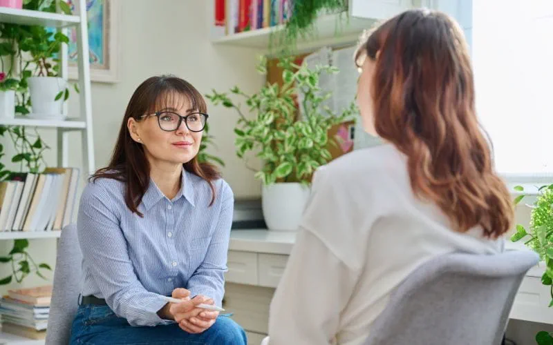 Une psychologue écoute attentivement une patiente dans un bureau lumineux Une psychologue écoute attentivement une patiente dans un bureau lumineux