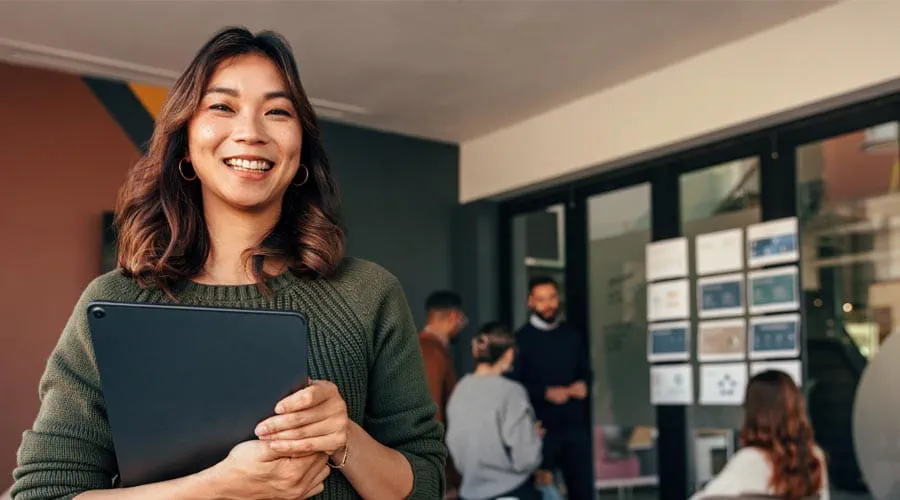 Smiling professional with a business meeting taking place in the background Smiling professional with a business meeting taking place in the background
