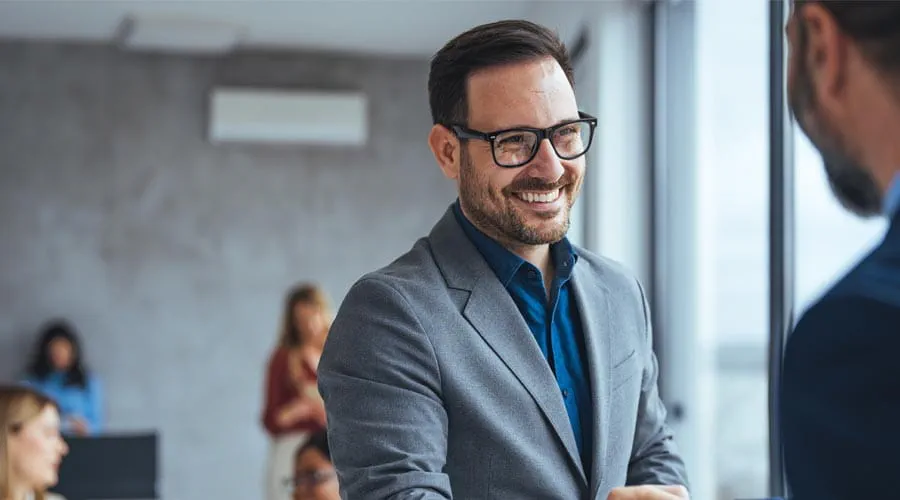 Smiling businessman shaking hands in a professional setting Smiling businessman shaking hands in a professional setting