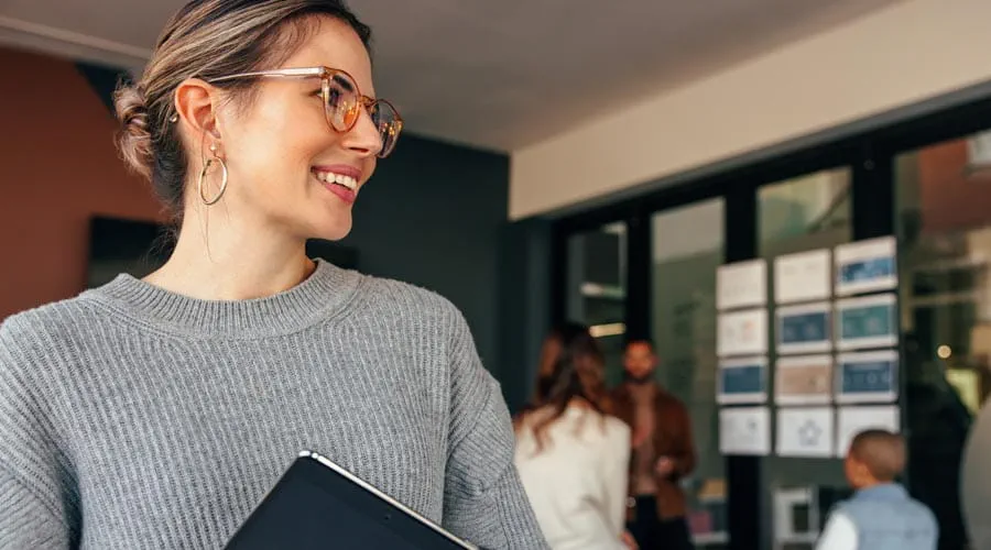 Smiling female professional holding a tablet in a modern office setting Smiling female professional holding a tablet in a modern office setting