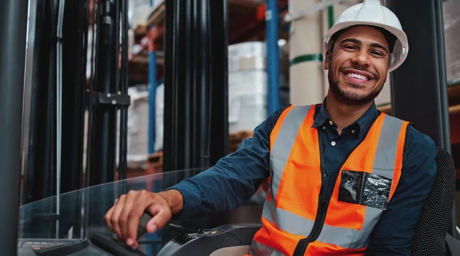 Male forklift driver smiling while working in a warehouse Male forklift driver smiling while working in a warehouse