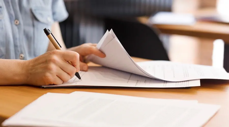 Professional signing a document at a desk in a modern office Professional signing a document at a desk in a modern office