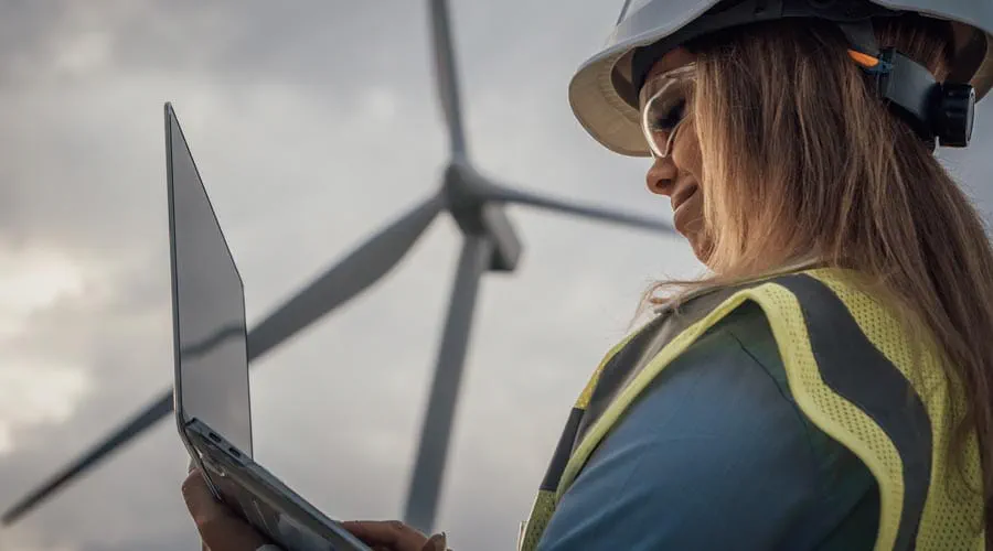 Engineer working on a laptop at a wind farm site Engineer working on a laptop at a wind farm site