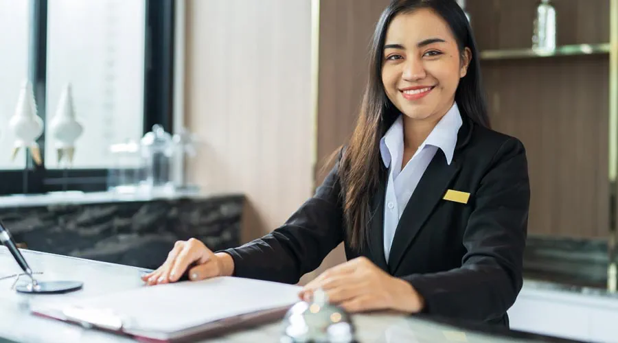 Friendly hotel receptionist welcoming guests at the front desk Friendly hotel receptionist welcoming guests at the front desk