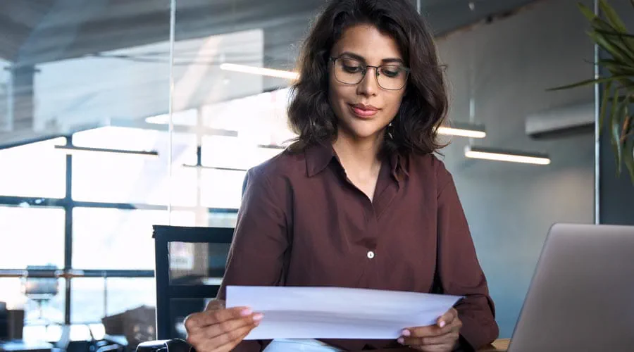 Business woman reading and analysing documents at her desk