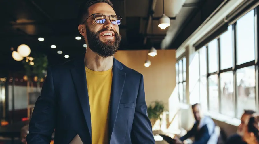 Male professional holding a laptop and smiling in a modern office Male professional holding a laptop and smiling in a modern office