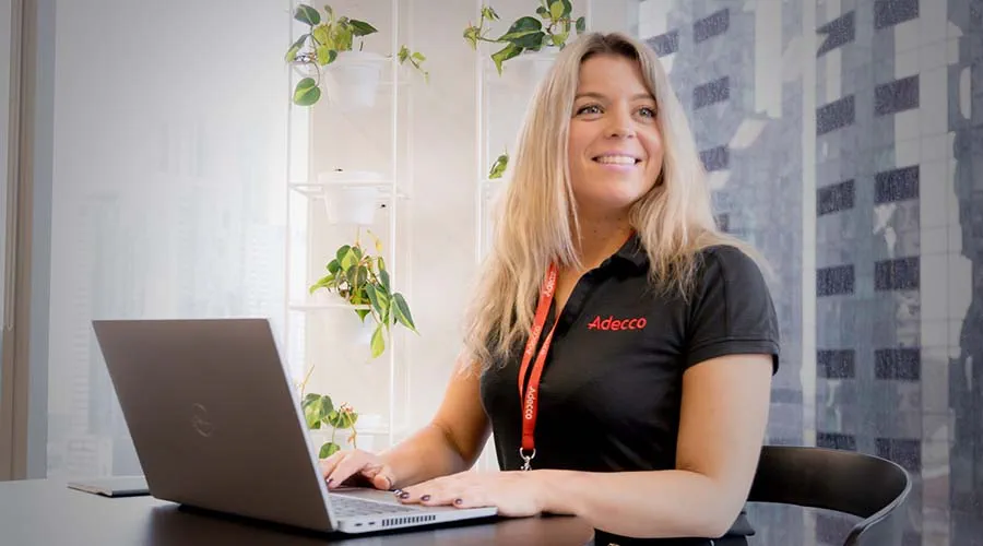 A woman working on a laptop while looking to the side. A woman working on a laptop while looking to the side.