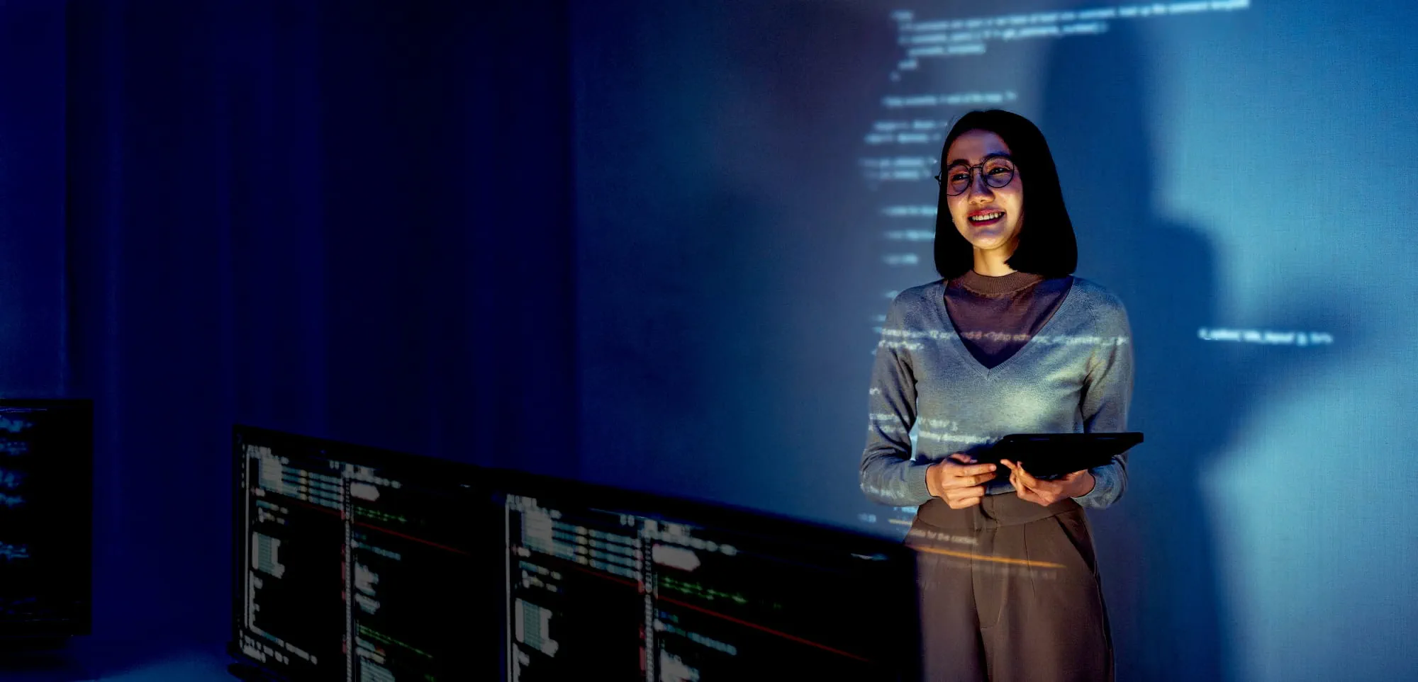 Personne tenant une tablette devant des projections de code et de données, illustration de l’intelligence artificielle et de l’avenir du travail. Personne tenant une tablette devant des projections de code et de données, illustration de l’intelligence artificielle et de l’avenir du travail.