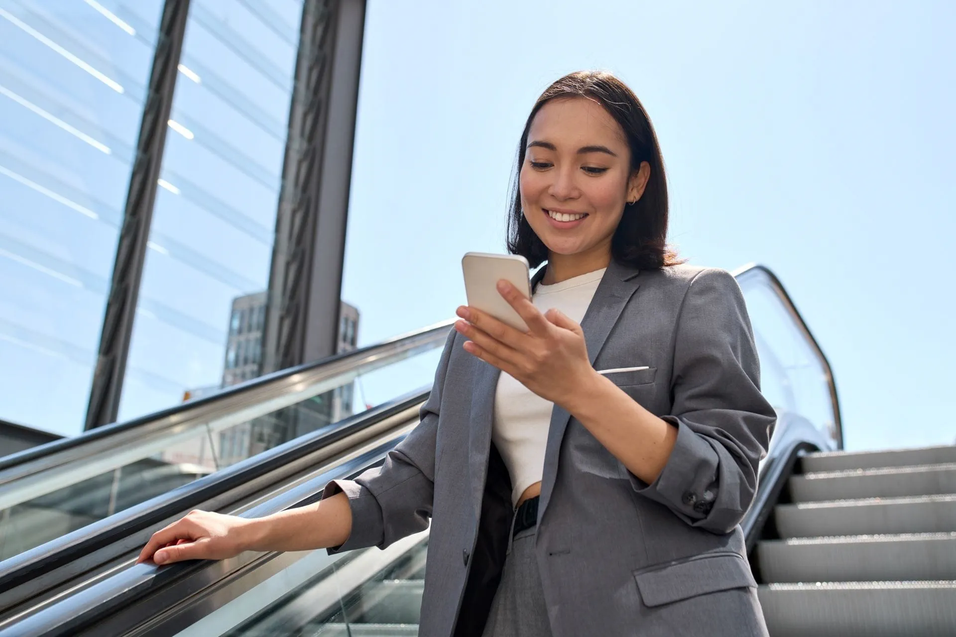 Una donna cammina per strada mentre guarda il suo smartphone.