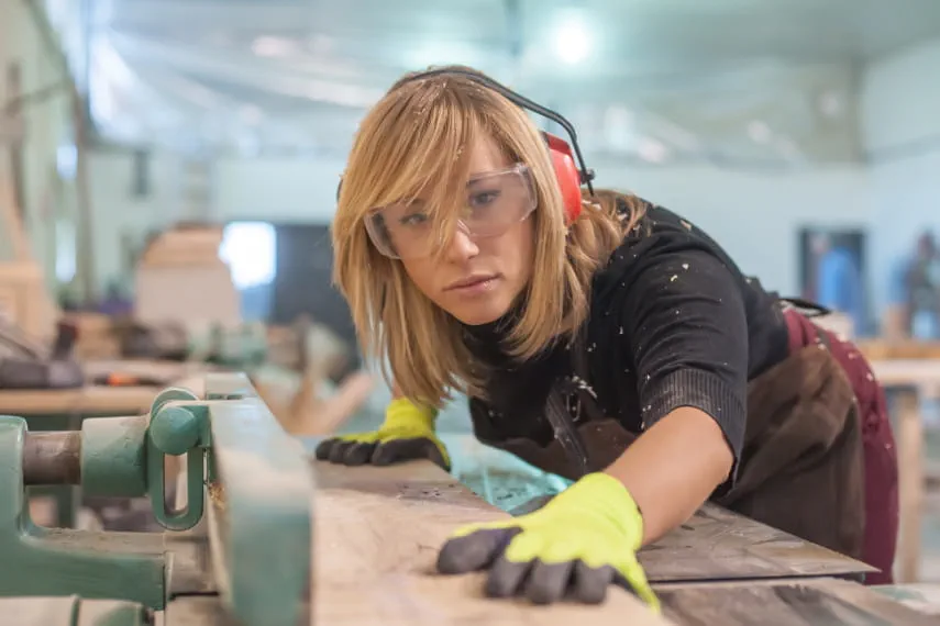 Handwerkerin arbeitet an der Säge Handwerkerin arbeitet an der Säge