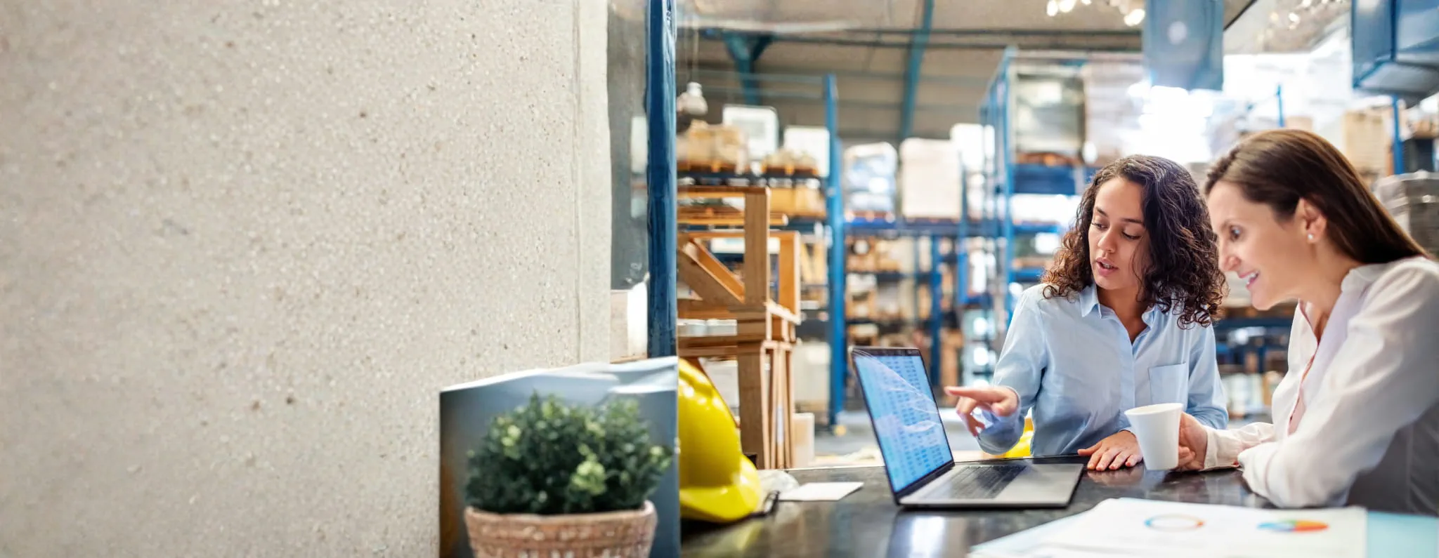 Zwei Frauen arbeiten gemeinsam an einem Laptop in einer Lagerumgebung. Zwei Frauen arbeiten gemeinsam an einem Laptop in einer Lagerumgebung.