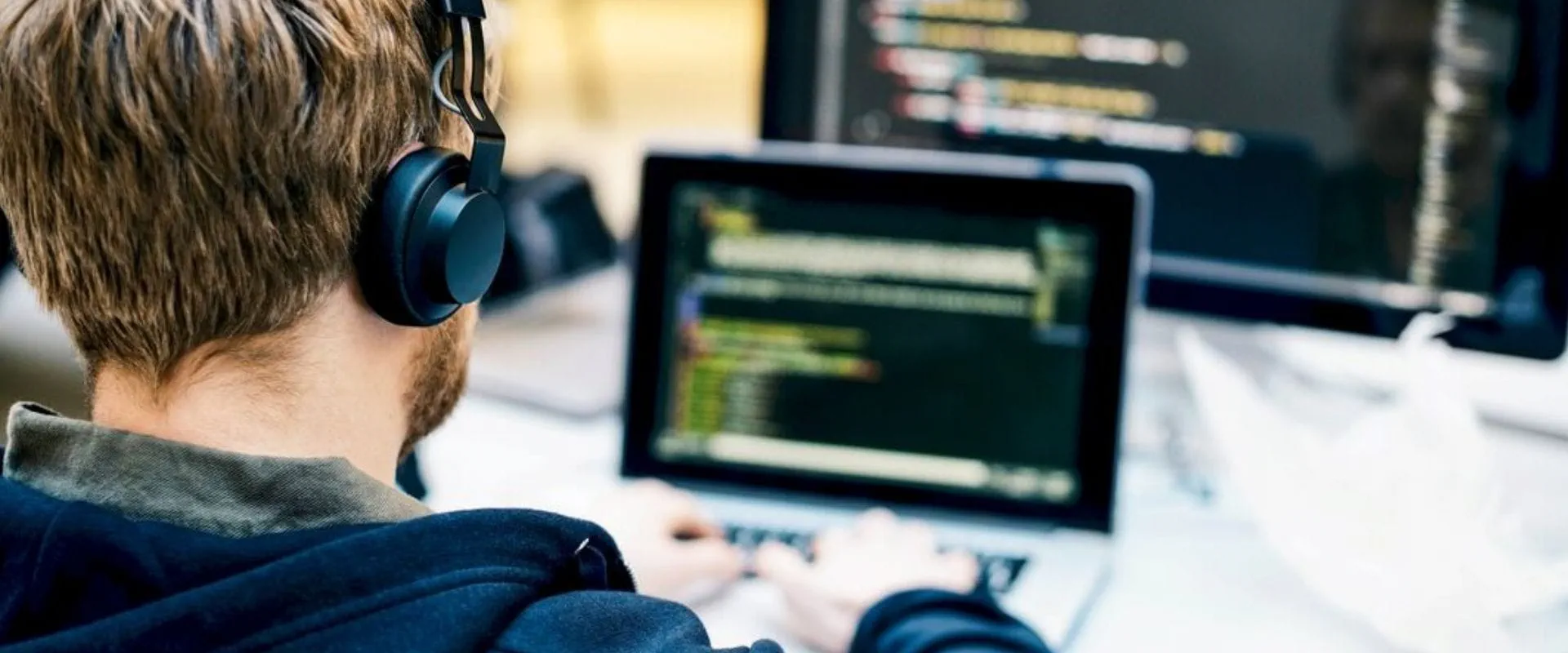 Man met koptelefoon achter laptop Man met koptelefoon achter laptop