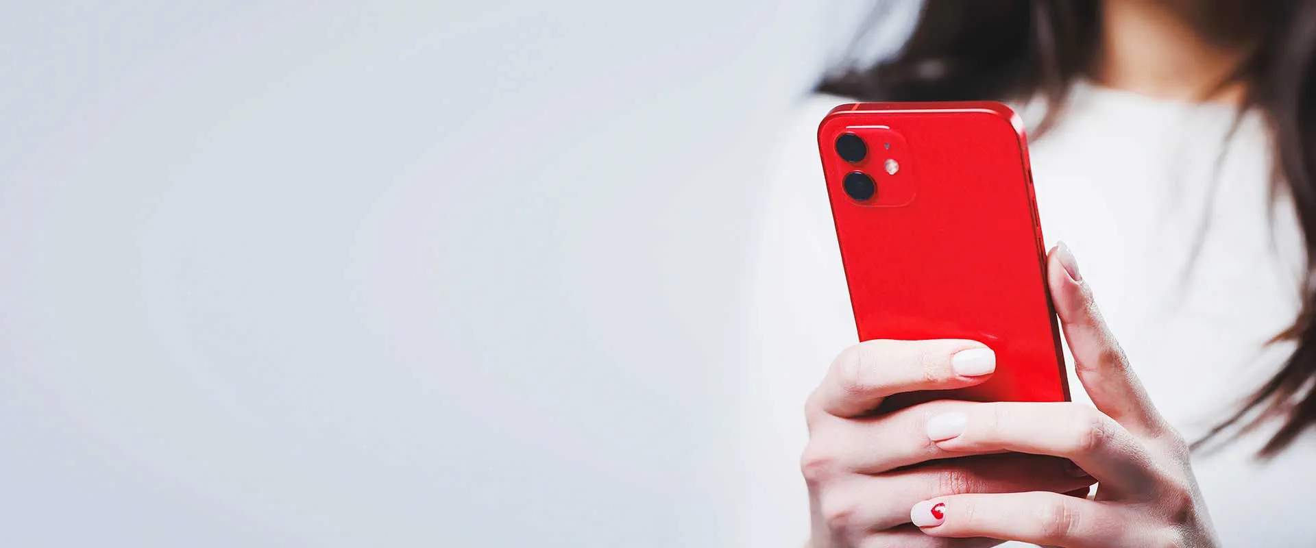 Person holding a red smartphone against a clean minimal background Person holding a red smartphone against a clean minimal background
