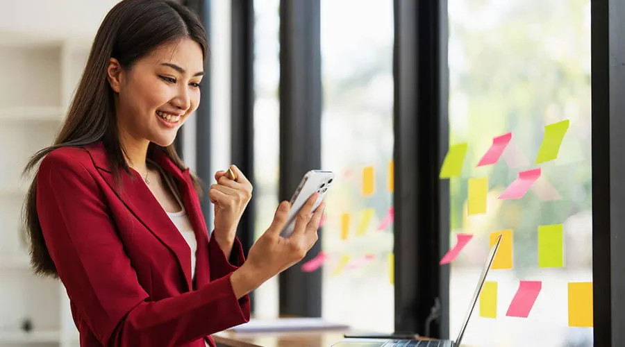 Woman using a mobile phone with a joyful expression Woman using a mobile phone with a joyful expression