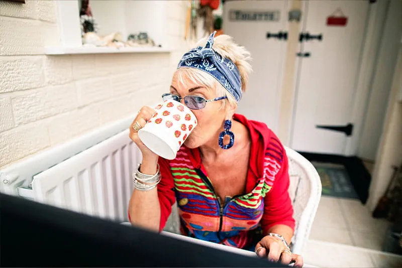 Professional working from home while drinking coffee and using a computer at a home office desk. Professional working from home while drinking coffee and using a computer at a home office desk.