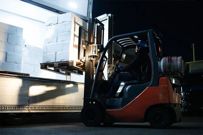 Forklift operator loading pallets onto a delivery truck at a busy warehouse during peak season. Forklift operator loading pallets onto a delivery truck at a busy warehouse during peak season.