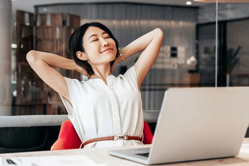 Woman relaxing at her desk after working on a laptop Woman relaxing at her desk after working on a laptop