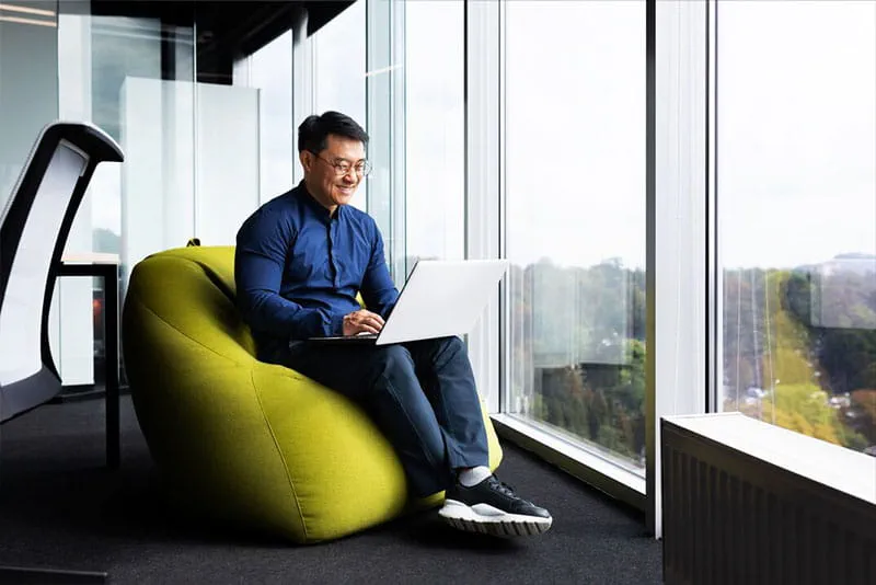 Professional smiling while using a laptop in a modern office, preparing for career opportunities. Professional smiling while using a laptop in a modern office, preparing for career opportunities.