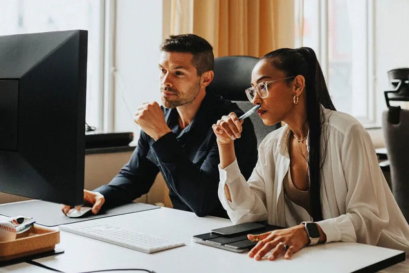 Two colleagues reviewing information on a computer in an office