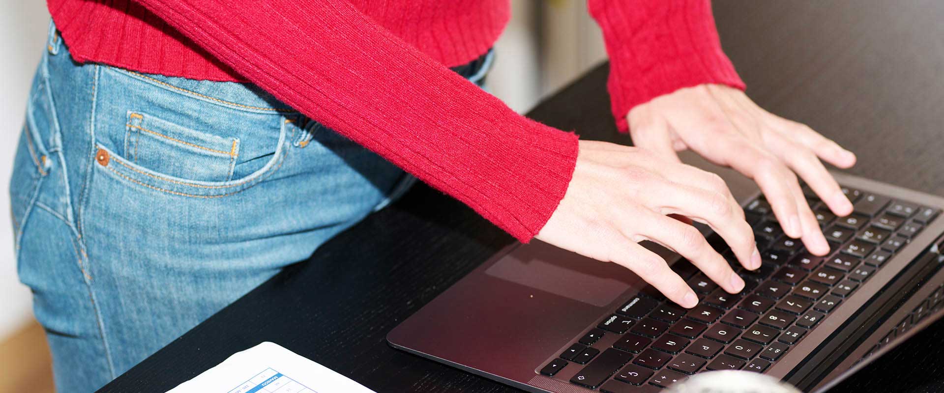 Personne travaillant sur un ordinateur portable à un bureau dans un espace de travail moderne Personne travaillant sur un ordinateur portable à un bureau dans un espace de travail moderne