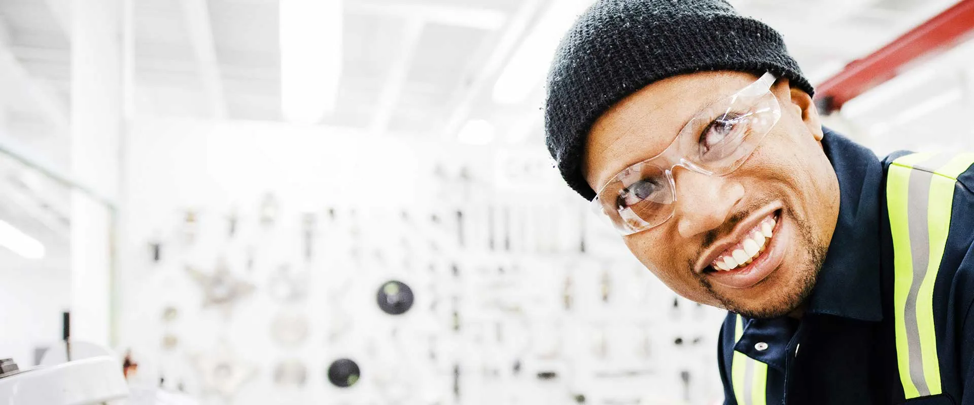 Industrial worker smiling in a workshop wearing safety gear Industrial worker smiling in a workshop wearing safety gear