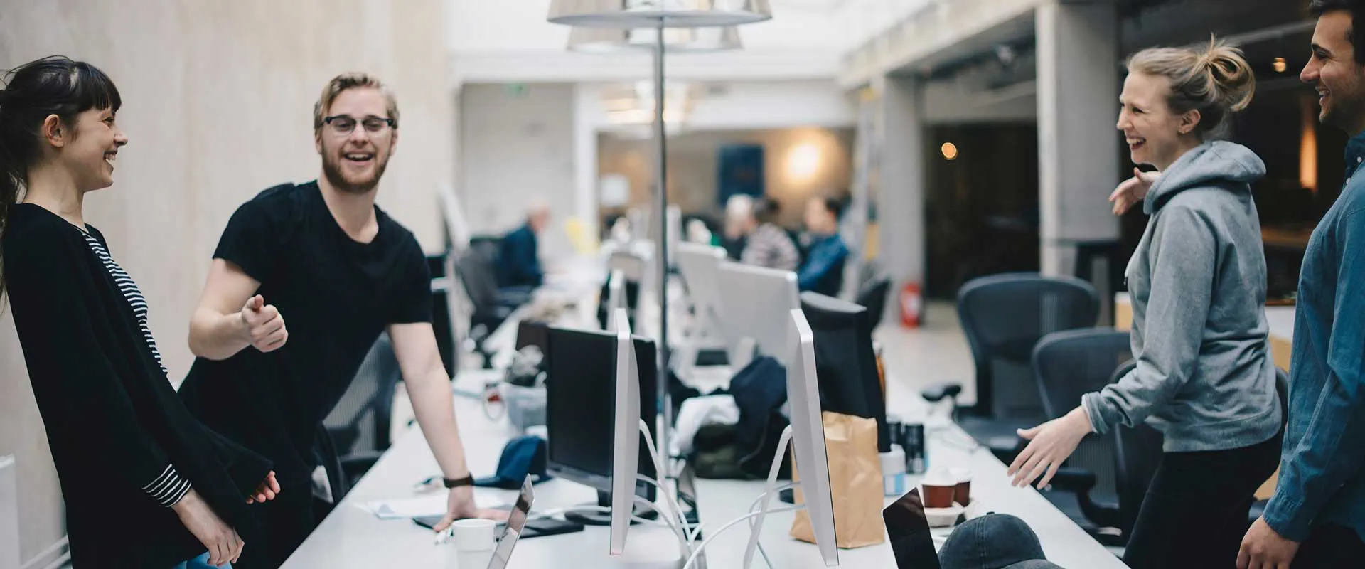 Kantoorteam staat en werkt samen rond bureaus in open werkruimte Kantoorteam staat en werkt samen rond bureaus in open werkruimte