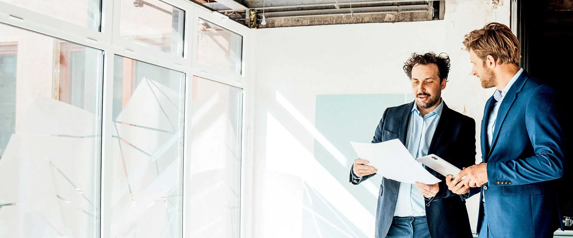 Dos profesionales discutiendo planos de construcción en un entorno de oficina Dos profesionales discutiendo planos de construcción en un entorno de oficina