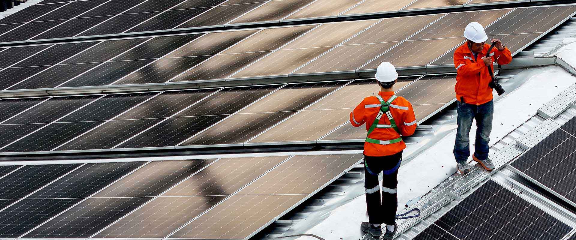 Two workers installing solar panels on rooftop Two workers installing solar panels on rooftop