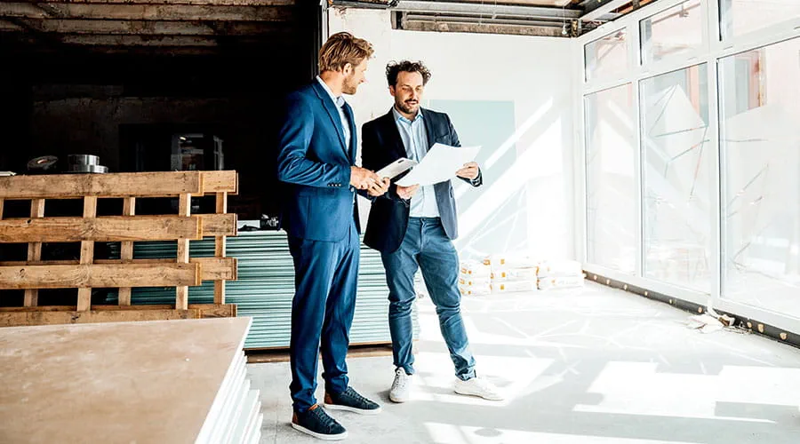 Two professionals walking through construction site