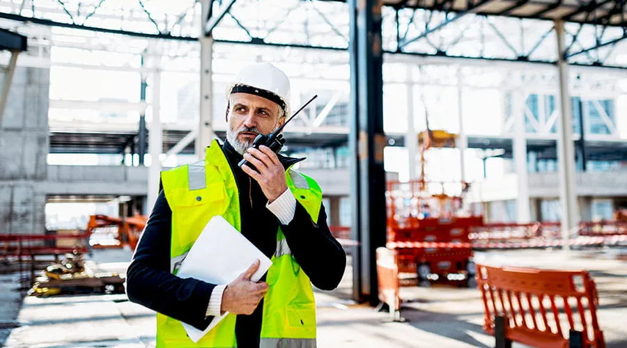 Chef de chantier parlant au téléphone en tenant des documents