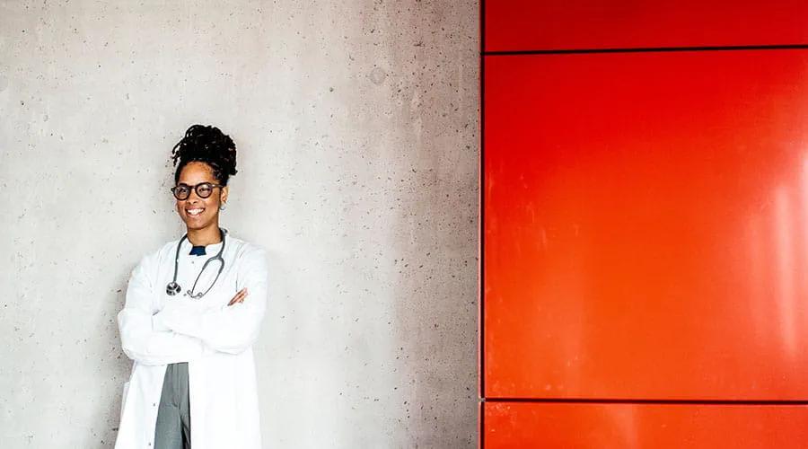Médico de pie contra una pared con un detalle rojo Médico de pie contra una pared con un detalle rojo