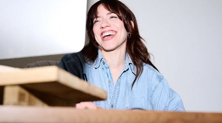 Woman smiling while holding box in warehouse setting Woman smiling while holding box in warehouse setting