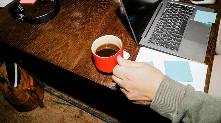 Personne travaillant sur un ordinateur portable avec du café sur le bureau