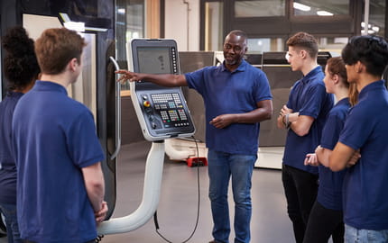 Un maître d'apprentissage montre une méthode de travail à deux alternants récemment recrutés. 