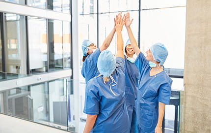 équipe de 4 soignants qui se dans un hôpital qui se félicitent d'une opération réussie 
