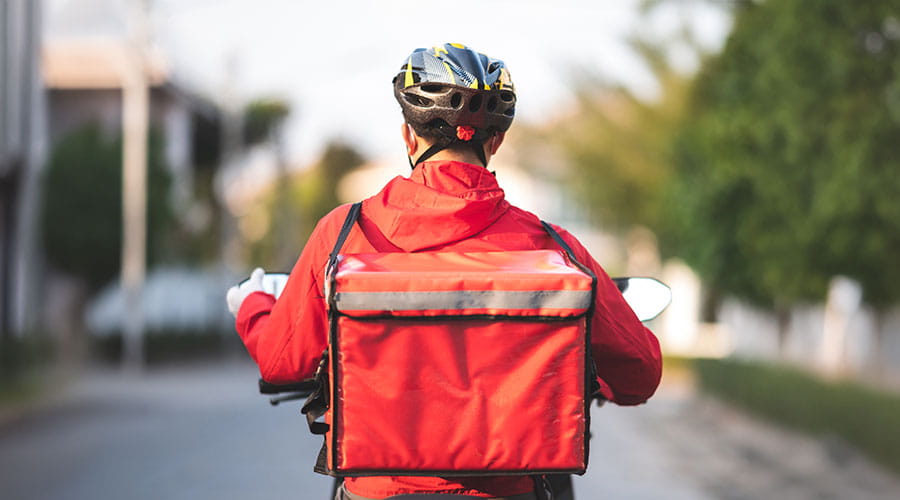 Repartidor montado en una bicicleta de espaldas con una mochila de color rojo Repartidor montado en una bicicleta de espaldas con una mochila de color rojo