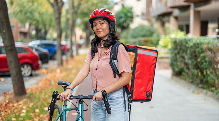 Repartidora montada en una bicicleta mirando a cámara Repartidora montada en una bicicleta mirando a cámara