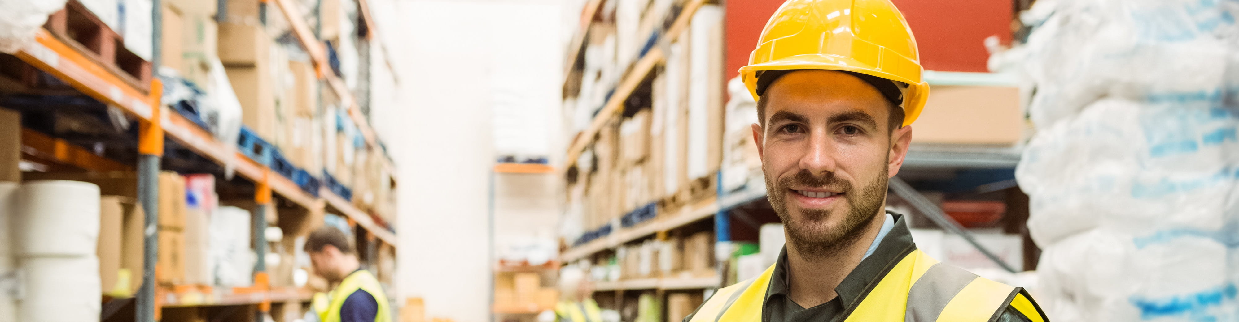 Un homme avec un casque jaune travaille dans le secteur de la logistique.