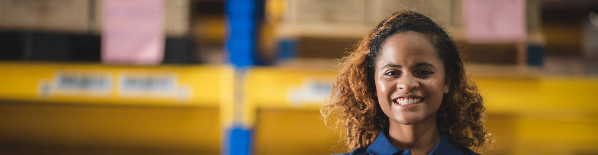 Une femme souriante dans un entrepôt.