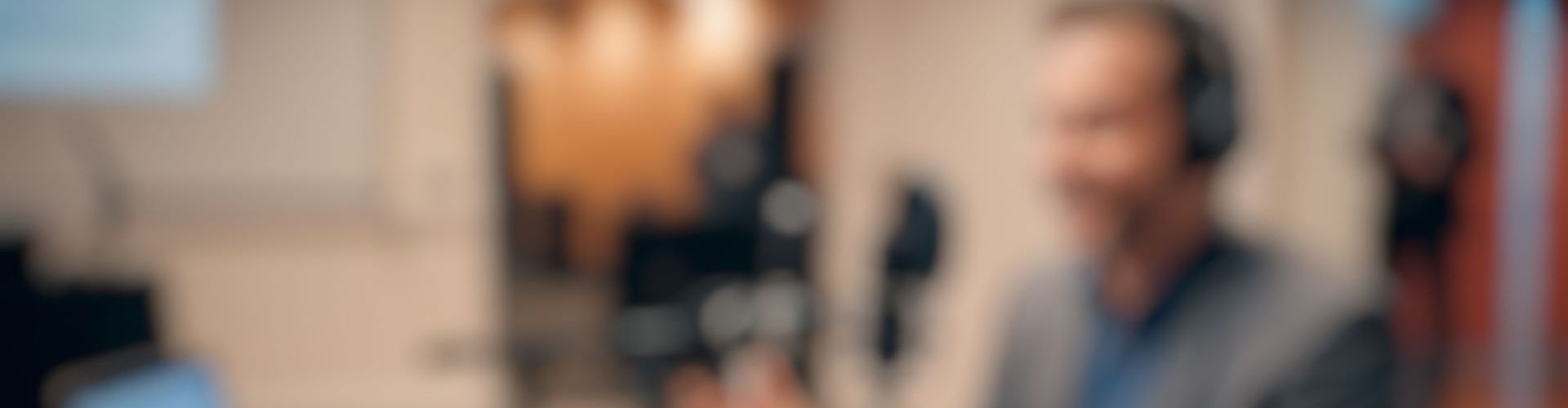 Un homme avec un casque devant un micro enregistrant un podcast