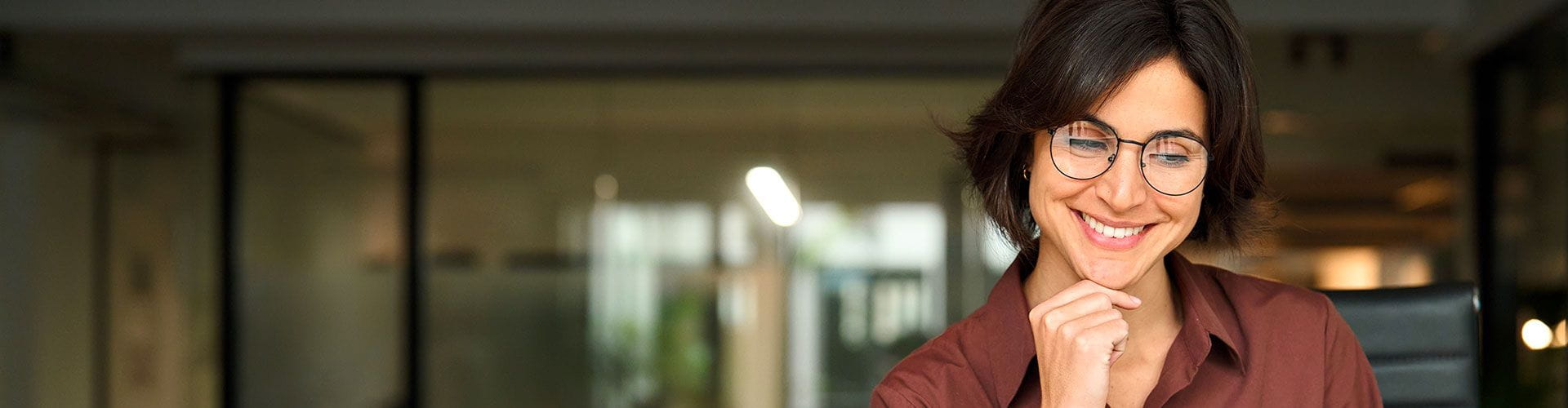 Deux personnes, un homme et une femme, se serrent la main au-dessus d'un bureau avec un ordinateur portable et des documents dans un bureau moderne