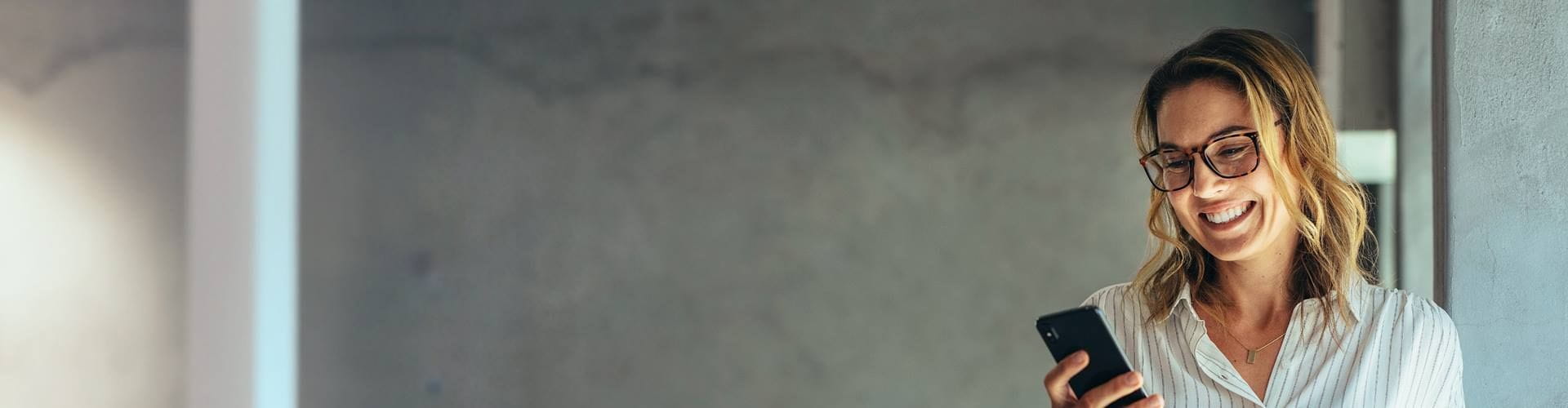 Intérimaire souriante utilisant son téléphone au bureau.