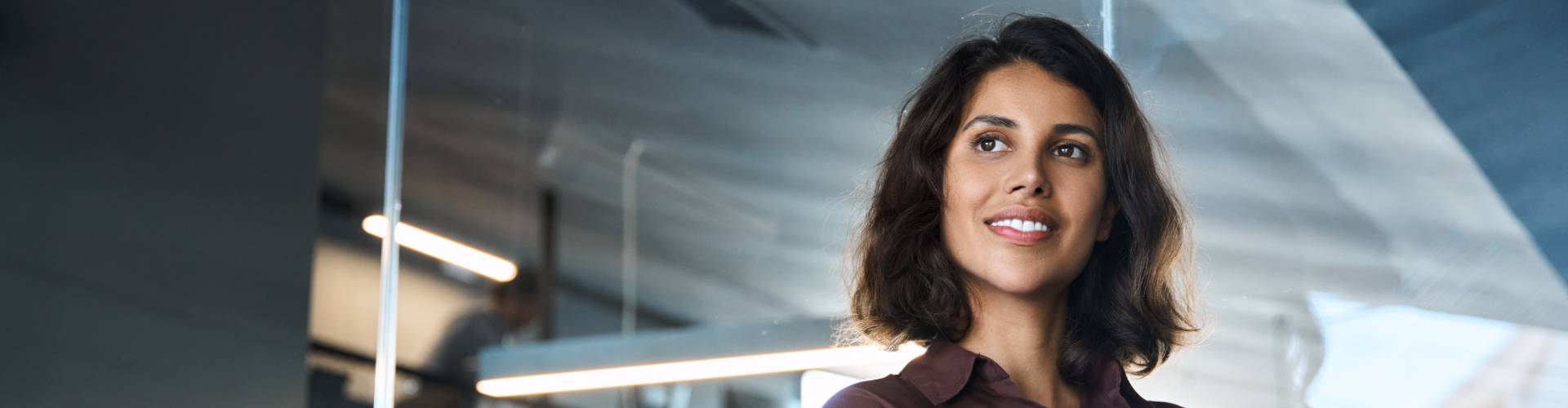 Une femme brune aux cheveux courts sourit.